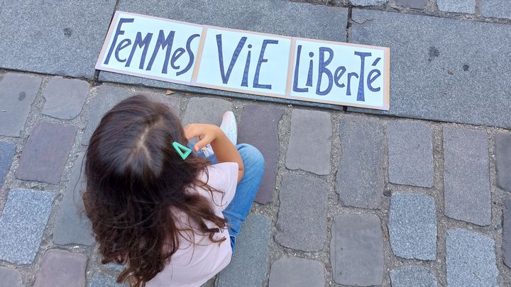 Une petite fille devant une pancarte avec le slogan scandé pendant la manifestation, dimanche 15 septembre 2024 à Paris. (AGATHE MAHUET / RADIO FRANCE)