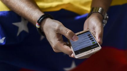 Un Vénézuelien utilise sont téléphone portable en Colombie, le 30 juillet 2017. (LUIS ROBAYO / AFP)