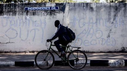 Un homme sur son vélo devant un graffiti sur un mur de Banjul, en Gambie, en janvier 2017 (photo d'illustartion).&nbsp; (SYLVAIN CHERKAOUI/AP/SIPA / AP)