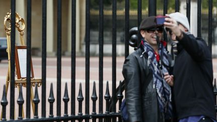 Des touristes prennent des "selfies" devant le bulletin royal install&eacute; dans la cour de Buckingham Palace, le 2 mai 2015. (STEFAN WERMUTH / REUTERS)