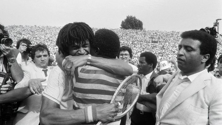 Yannick Noah dans les bras de son père Zacharie après sa victoire en finale de Roland-Garros, le 5 juin 1983 (DOMINIQUE FAGET / AFP)