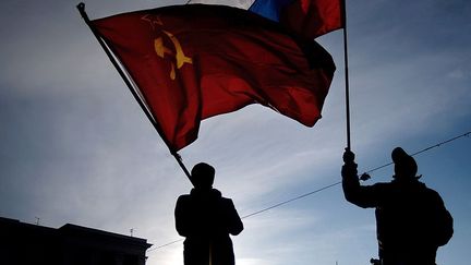 A Simféropol, deux hommes brandissent les drapeaux de l'URSS et de la Russie. (FILIPPO MONTEFORTE / AFP)