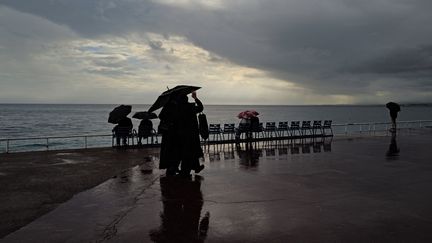 Des personnes sous un parapluie à Nice, le 17 octobre 2024. (VALERY HACHE / AFP)