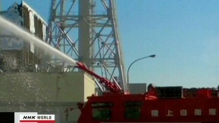 Un camion de pompiers arrose le réacteur 3 de la centrale de Fukushima pour tenter de le refroidir (19 mars 2011) (AFP / NHK)