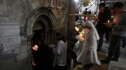 entrent dans la grotte de l'église de la Nativité, qui mesure 12,3 mètres de long, pour 3,5 de large et 3 mètres de hauteur. (MUSA AL SHAER / AFP)