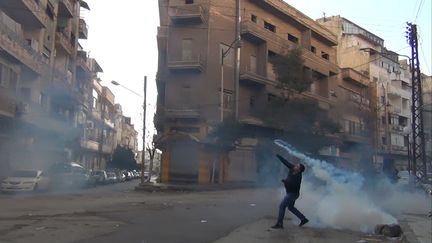 Un manifestant jette une grenade lacrymog&egrave;ne sur les forces de s&eacute;curit&eacute;, le 27 d&eacute;cembre 2011, &agrave; Homs (Syrie).&nbsp; (STR / AFP)