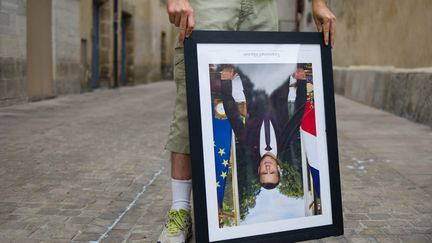 Un homme&nbsp;tient un portrait d'Emmanuel Macron décroché, lors d'une manifestation à Bayonne, le 25 août 2019. (ALEKSANDER KALKA / NURPHOTO)