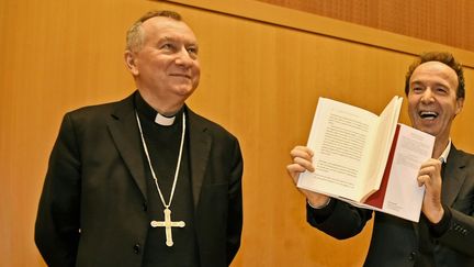 Roberto Benigni brandit le livre du pape en compagnie du cardinal Pietro Parolin.
 (ALBERTO PIZZOLI / AFP)