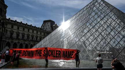 Banderole déployée par l'association américaine PAIN (Pain Addiction Intervention Now), le 1er juillet devant la Pyramide du Louvre à Paris (STEPHANE DE SAKUTIN / AFP)