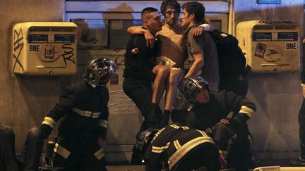 Un homme en état de choc est pris en charge par des pompiers, le 13 novembre 2015, à Paris. (CHRISTIAN HARTMANN / REUTERS)