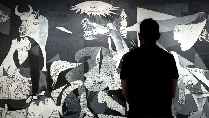 Un visiteur regarde le chef-d'œuvre du peintre espagnol Pablo Picasso "Guernica" lors&nbsp;de&nbsp;la conférence de presse présentant les événements de "l'Année Picasso", marquant le 50e anniversaire de la mort du peintre, au musée Reina Sofia de Madrid, le 12 septembre 2022 (THOMAS COEX / AFP)