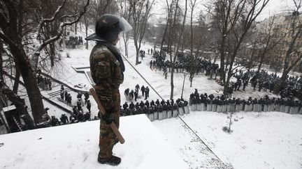 Un manifestant observe un cordon policier, le 21 janvier 2014, &agrave; Kiev (Ukraine). (VASILY FEDOSENKO / REUTERS)