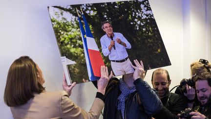  Des personnes tentent de raccrocher une photo de Francois Fillon tombée accidentellement avant une conference de presse du candidat. (NICOLAS KOVARIK / MAXPPP)