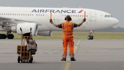 Un agent de piste guide un avion d'Air France sur le tarmac de l'a&eacute;roport de Lille (Nord), le 9 juin 2014. (DENIS CHARLET / AFP)