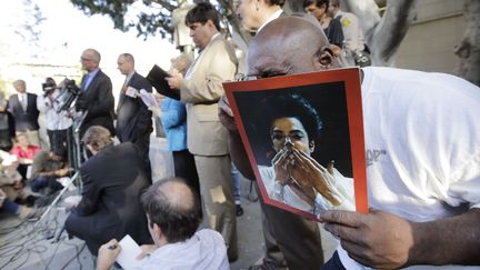 Un fan de Michael Jackson exhibant une photo du chanteur morten 2009, le 2 octobre 2013, &agrave; la sortie du tribunal de Los Angeles (Etats-Unis) o&ugrave; la famille du "Roi de la pop" vient de perdre son proc&egrave;s contre le promoteur de la star. (JAE C. HONG / AP / SIPA)