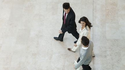 Une femme et deux hommes marchent et parlent ensemble. (MAXPPP)