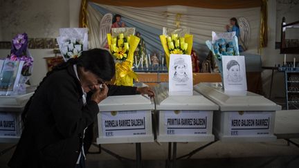 Une personne se recueille près du cercueil contenant les restes d'une victime du massacre d'Accomarca, le 18 mai 2022, dans le sud du Pérou. (ERNESTO BENAVIDES / AFP)