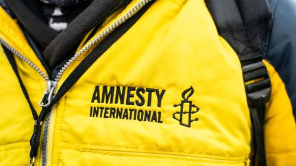 Un manifestant contre l'extrême droite porte un gilet aux couleurs de l'ONG Amnesty International, le 11 décembre 2021, place de la République à Paris. (HANS LUCAS)