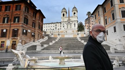 Un homme portant un masque de protection marche sur la Piazza di Spagna, à Rome (Italie), le 12 mars 2020. (ALBERTO PIZZOLI / AFP)