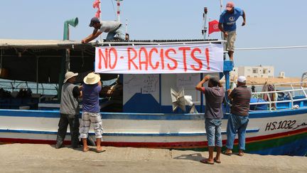 Des pêcheurs tunisiens accrochent une banderole antiraciste dans le port de&nbsp;Zarzis, dans le sud-est de la Tunisie, le 6 août 2017. (FATHI NASRI / AFP)