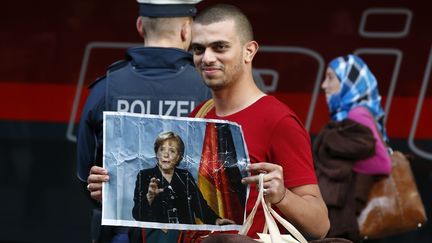 Un migrant brandit une photo de la chanceli&egrave;re allemande Angela Merkel &agrave; son arriv&eacute;e en gare de Munich (Allemagne), le 5 septembre 2015. (MICHAEL DALDER / REUTERS)