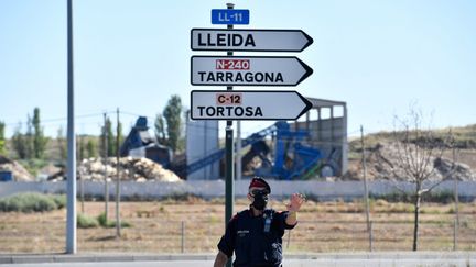 Un policier catalan contrôle les allers et venues des voitures, le 4 juillet 2020, sur une route de&nbsp;Lérida&nbsp;(Espagne). (PAU BARRENA / AFP)