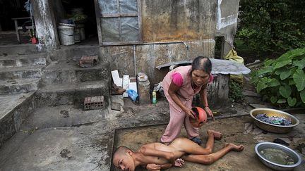 une femme qui vit elle aussi dans la province de Quang Binh, lave son fils handicapé Doan Van Quy.  (REUTERS/Damir Sagolj )