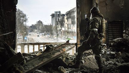 Un soldat russe patrouille dans les ruines du théâtre de Marioupol (Ukraine), en avril 2022 (ALEXANDER NEMENOV / AFP)