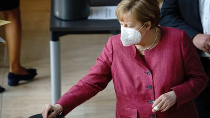 Angela Merkel glisse son bulletin dans l'urne lors du vote de la loi permettant la mise en place d'un couvre-feu national contre le Covid-19 au Bundestag, à Berlin, mercredi 21 avril 2021. (KAY NIETFELD / DPA)