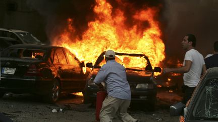 Un homme tente d'&eacute;teindre l'incendie apr&egrave;s un attentat &agrave; la voiture pi&eacute;g&eacute;e, le 9 juillet 2013 &agrave; Beyrouth (Liban). (REUTERS)