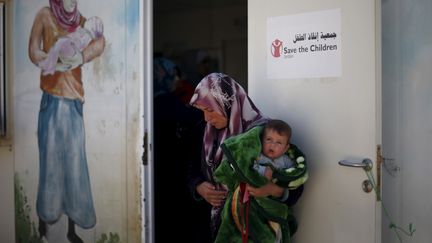 Une femme syrienne réfugiée avec son fils attend devant la permanence de l'ONG "Save the Children" dans un camp en Jordanie, le 4 février 2016. (MUHAMMAD HAMED / REUTERS)