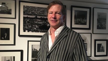 Le joaillier Lorenz Bäumer dans sa boutique de la place Vendôme à Paris pose devant un mur de photographies en noir et blanc consacrées à la colonne Vendôme, en juin 2022 (Corinne Jeammet)