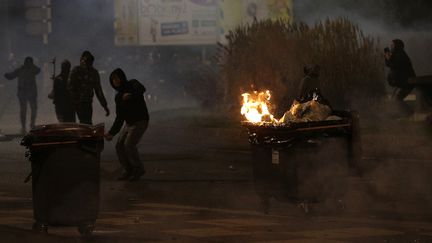 Des personnes cagoulées se tiennent derrière une poubelle incendiée, le 11 février 2017, lors d'incidents à Bobigny (Seine-Saint-Denis). (GEOFFROY VAN DER HASSELT / AFP)