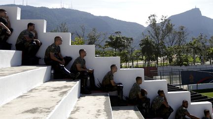 Des soldats br&eacute;siliens se prot&egrave;gent su soleil tandis qu'ils assistent &agrave; un entra&icirc;nement de l'&eacute;quipe de football des Pays-Bas &agrave; Rio de Janeiro (Br&eacute;sil), le 8 juin 2014. (RICARDO MORAES / REUTERS)