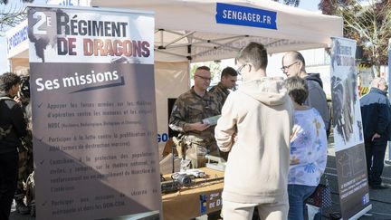 France, 2024-09-28. Sur le stand d'un regiment est inscrit en grosses lettre : S'engager.fr. L armee recrute et une famille s'informe sur les roles de ce corps d'armee. (JEAN FRANCOIS FORT / HANS LUCAS / AFP)