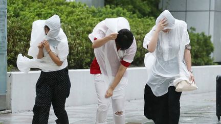 Des habitants de Nagoya (Japon) traversent la rue battue par les vents, le 4 septembre 2018. (JIJI PRESS / AFP)