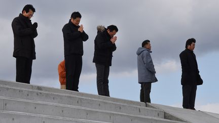 Des Japonais prient, vendredi 11 mars 2016, sur les côtes de Sendai (Japon), en hommage aux victimes du séisme, du tsunami et de la catastrophe nucléaire de Fukushima, survenus cinq ans plus tôt.&nbsp; (TORU YAMANAKA / AFP)