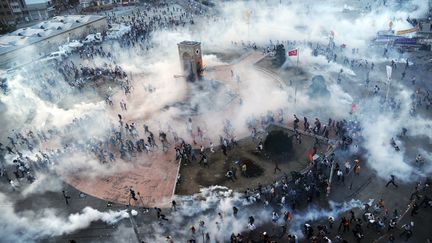 Des manifestants s'enfuient alors que les policiers antiémeute turcs tirent des gaz lacrymogènes sur la place Taksim, le 11 juin 2013 à Istanbul. Parti d'une initiative d'écologistes et de riverains qui s'opposaient à la destruction d'un parc, le mouvement de protestation a rapidement pris de l'ampleur, avec des manifestations réunissant jusqu'à 2,5 millions de personnes dans tout le pays. (BULENT KILIC / AFP)