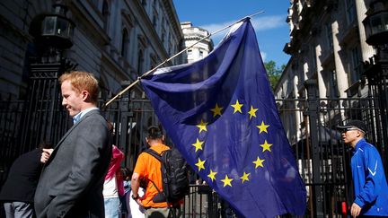 Un homme porte un drapeau de l'Union européenne, devant le 10, Downing Street à Londres (Royaume-Uni), le 24 juin 2016. (NEIL HALL / REUTERS)