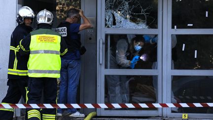 Un officier de police judiciaire et de police scientifique inspectent l'entrée de l'immeuble où un incendie s'est déclaré dans le quarties des Moulins à Nice, le 18 juillet 2024. (VALERY HACHE / AFP)