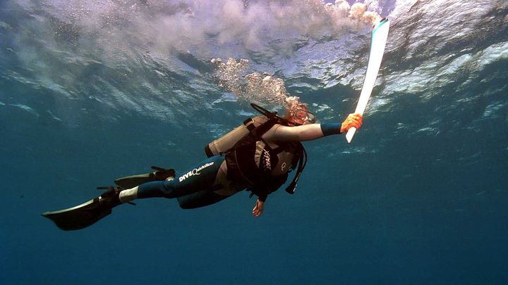 La torche a brûlé sous l'eau, à plus de 2000°C, pendant 2 minutes et 40 secondes.  C'est la méthode trouvée par quatre scientifiques australiens, permettant à la biologiste Wendy Craig-Duncan de visiter la Grande Barrière de Corail avec la flamme olympique des Jeux de Sydney, le 27 juin 2000. (SIPA)