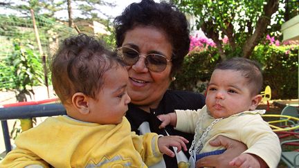 Aicha Ech-Channa, tenant deux bébés dans le jardin de son association pour mères en difficulté, à Casablanca, en mai 2000. (ABDELHAK SENNA / AFP)