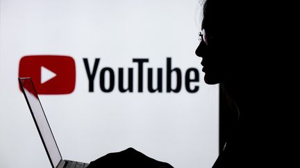 Une femme utilise un ordinateur devant un logo Youtube, le 18 juillet 2018, à Ankara, en Turquie.&nbsp; (AYTAC UNAL / ANADOLU AGENCY / AFP)