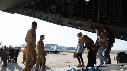 Des militaires français aident des évacués à débarquer d'un avion en provenance de Kaboul, à Abou Dhabi (Emirats Arabes Unis), le 26 août 2021. (EYEPRESS NEWS / AFP)