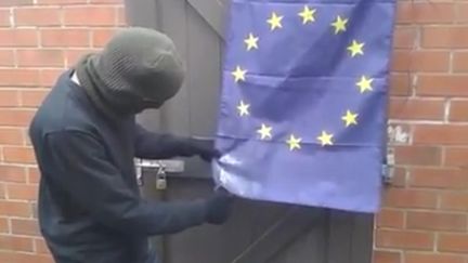 Capture d'écran d'une vidéo montrant un homme cagoulé en train de mettre le feu à un drapeau européen, publiée le 27 mars 2015 sur Facebook. (BALACLAVA FLAG GIMP / FACEBOOK)