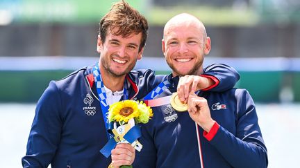 Les sourires de Hugo Boucheron (à gauche) et Matthieu Androdias sur le podium après leur victoire en aviron deux de couple, le 28 juillet à Tokyo. (CHARLY TRIBALLEAU / AFP)