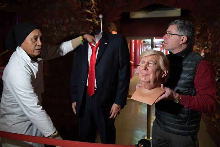 Le sculpteur Eric Saint Chaffray s'apprête à poser la tête de cire de Donald Trump sur le buste.&nbsp; (CHRISTOPHE ARCHAMBAULT / AFP)