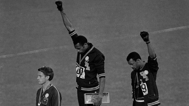 Les Am&eacute;ricains Tommie Smith (au centre) et John Carlos (&agrave; droite) brandissent un poing gant&eacute; de noir sur le podium du 200 m aux Jeux olympiques de Mexico, le 16 octobre 1968.&nbsp; (AP / SIPA)