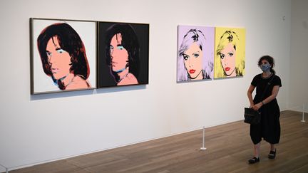 Une visiteuse masquée, virus oblige, passe dans une salle de l'exposition Andy Warhol à la Tate Modern de Londres, le 24 juillet 2020. (DANIEL LEAL-OLIVAS / AFP)