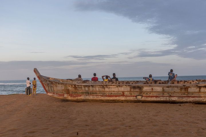 Des pêcheurs s'appuient sur un pirogue sur la plage près du site de construction du nouveau port de Lomé, le 2 juin 2018.  (YANICK FOLLY/AFP)